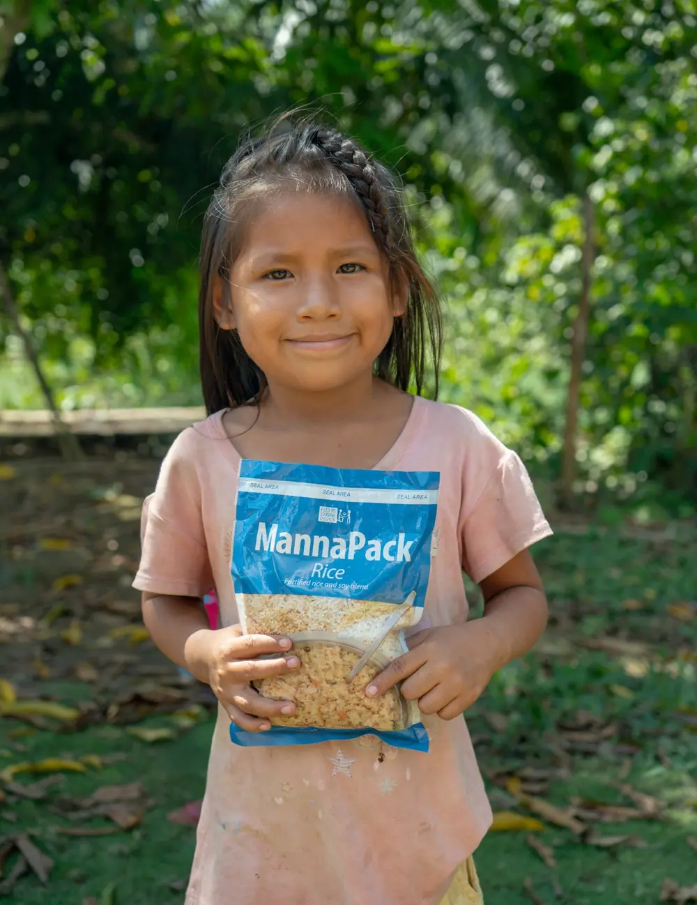 Niña sosteniendo un paquete de MannaPack en una comunidad amazónica